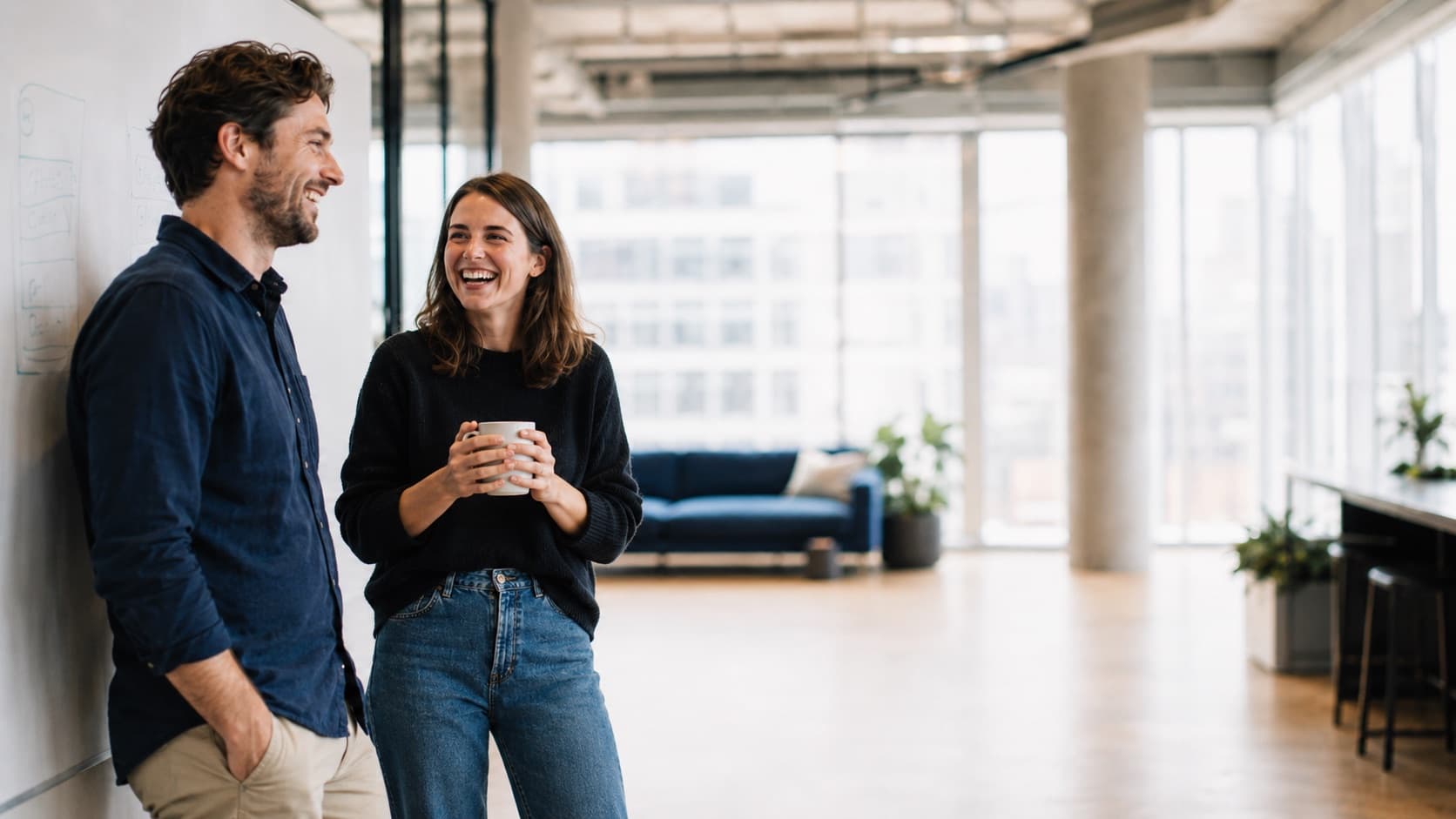 Two colleagues talking through a project in a bright studio office
