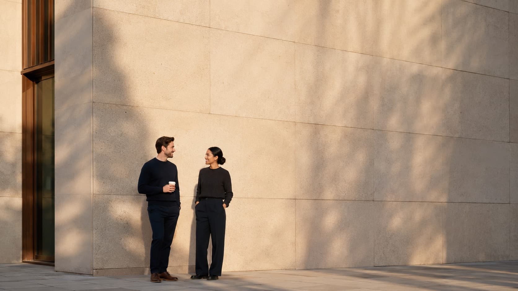 Two founders talking beside a limestone wall in morning light